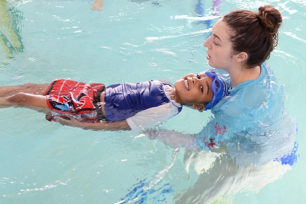 Swim instructor supports child floating on back, building independence in Charlotte & Huntersville