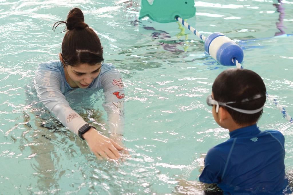 Instructor teaching a child float and kick skills in Charlotte & Huntersville, NC