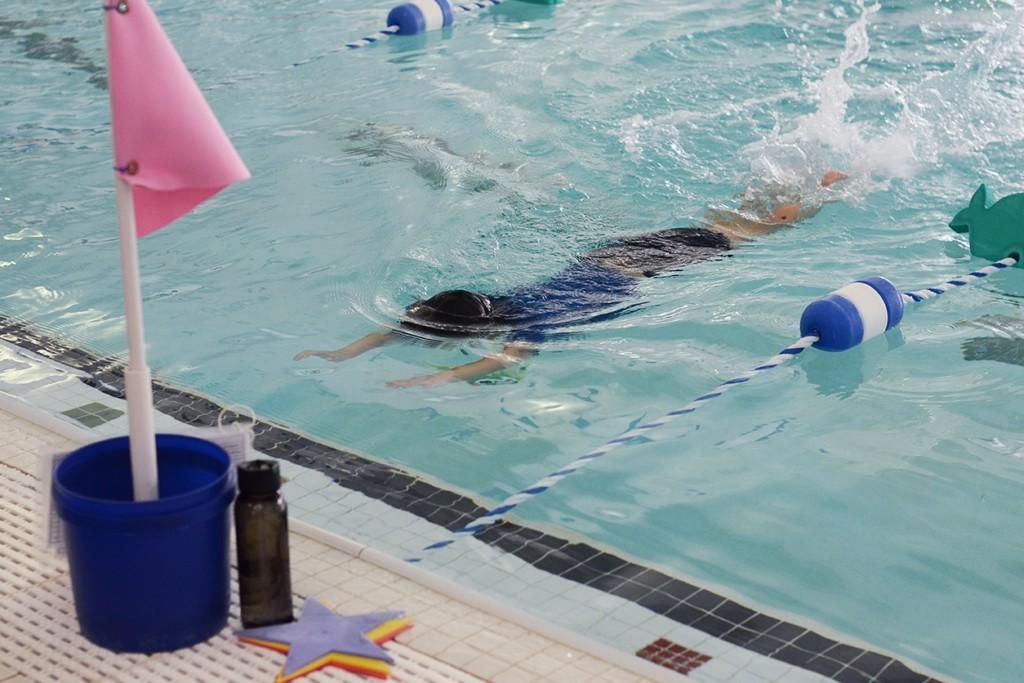 Child practicing float and kick with instructor in heated pool in Charlotte & Huntersville, NC