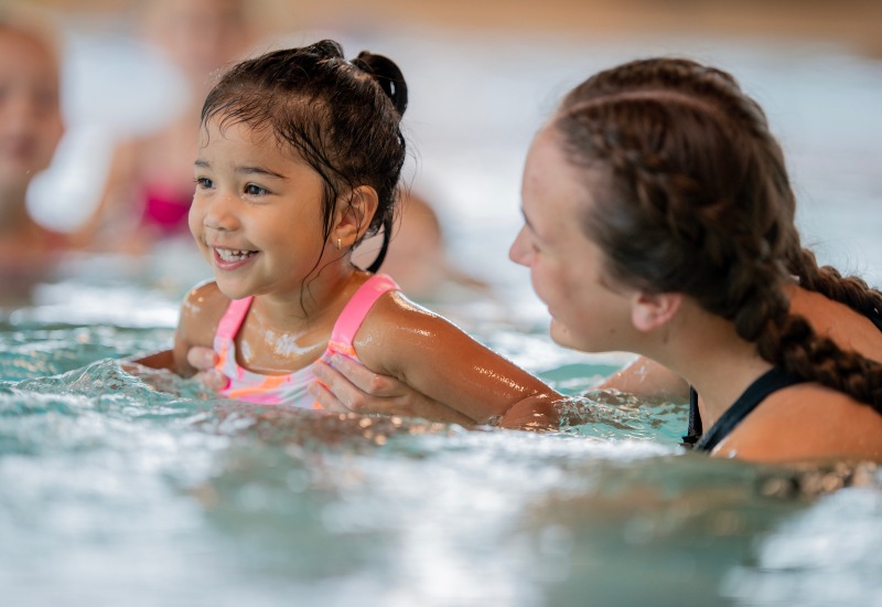 A girl with a swim instructor, highlighting ADHD-friendly swimming in Huntersville & Charlotte, NC