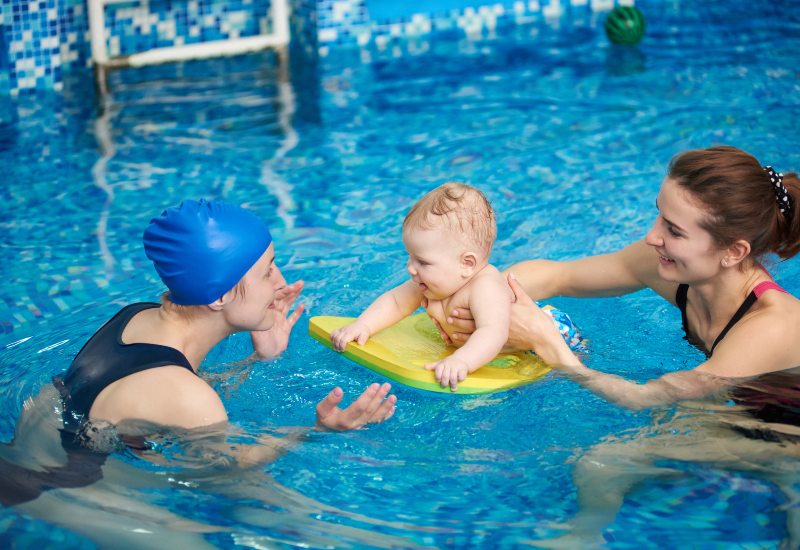A swim Instructor supporting a baby during a first swim lesson in Huntersville and Charlotte, NC