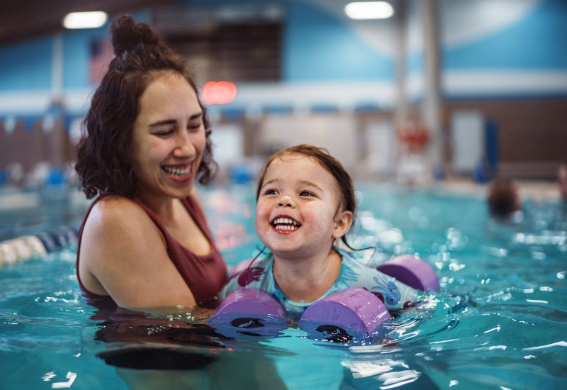 Instructor helps child swim faster during swimming lessons in Huntersville & Charlotte, NC